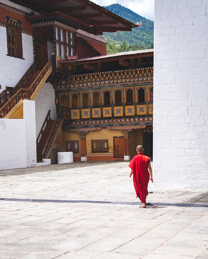 A monk walks through a traditional Bhutanese monastery courtyard in Thimphu, showcasing Bhutanese architecture.